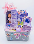 A themed toy and mystery box gift basket featuring the Aphmau brand, including a boxed doll, various colorful mystery packages, and a pink ribbon bow, all arranged in a gray plastic basket decorated with stickers.